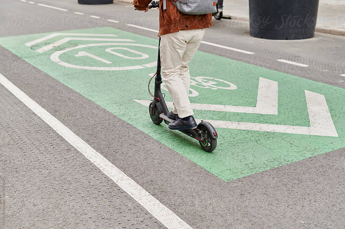 Man riding an e-scooter along a bike path