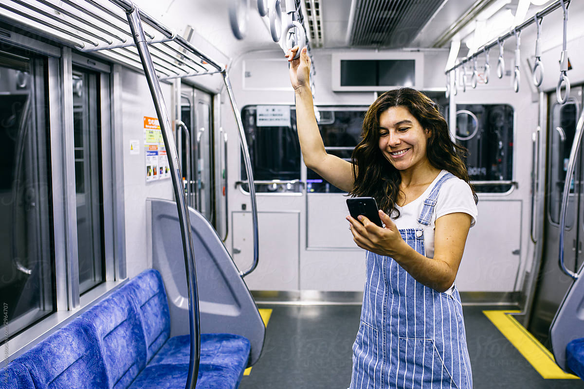 Delighted woman using smartphone in train
