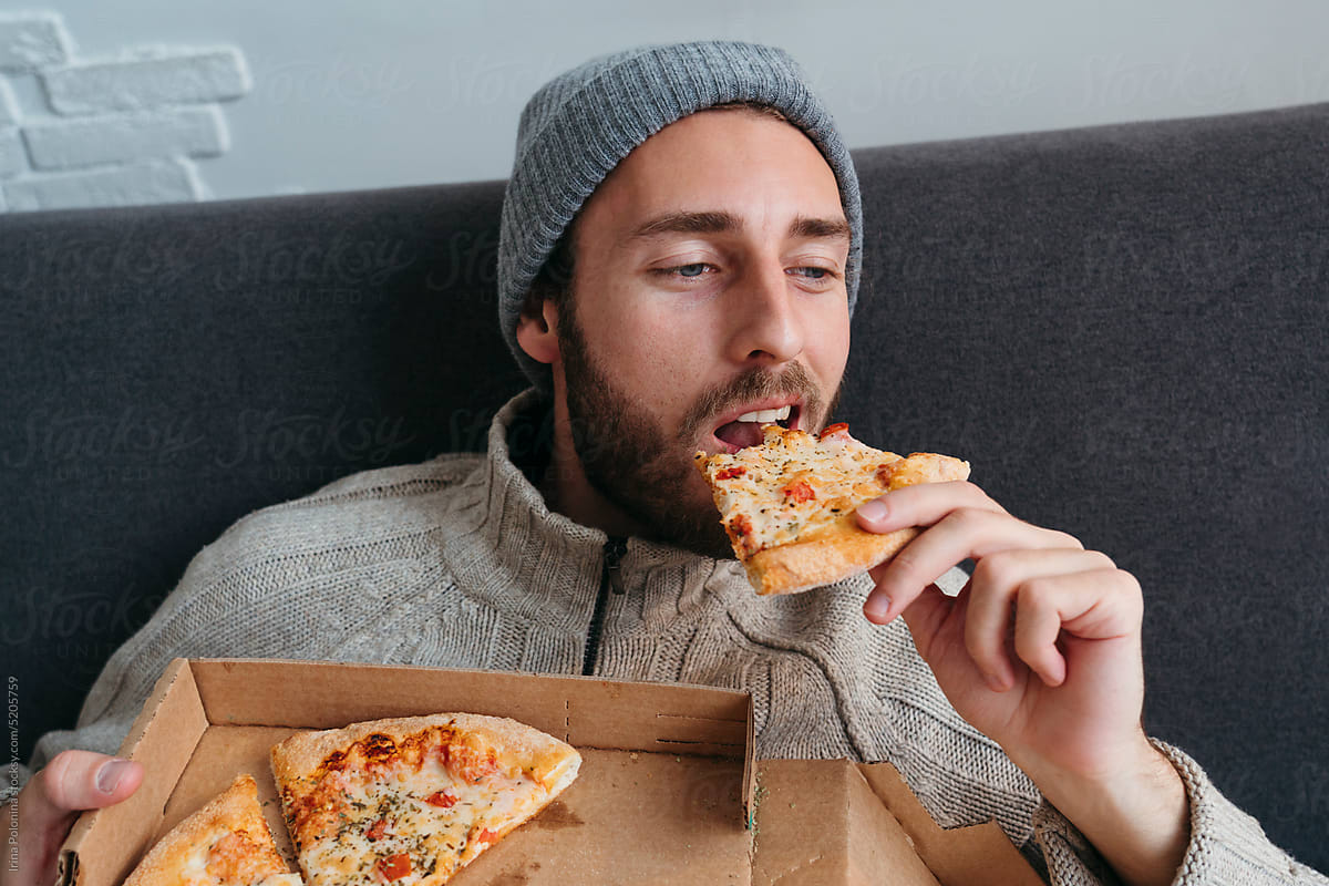 Modern male eats pizza.