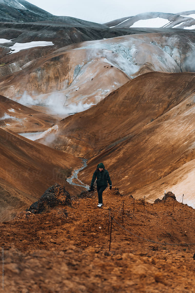 Hiker climbs up exploring brown landscape of Iceland.