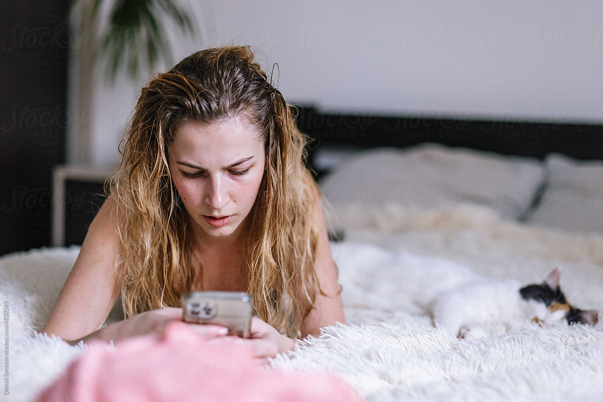 Young girl holding smartphone and relaxing in bedroom