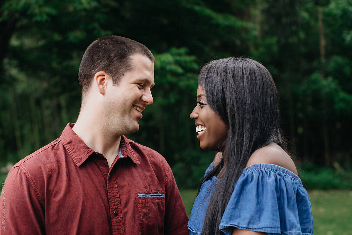 Interracial Couple Looking At Each Other And Smiling Del Colaborador De Stocksy Leah Flores