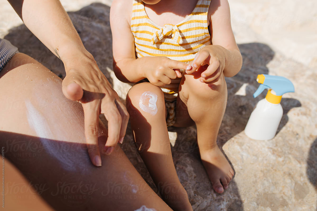 Mother and daughter applying sunscreen