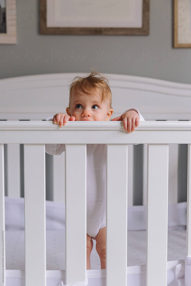 Baby stands in crib.