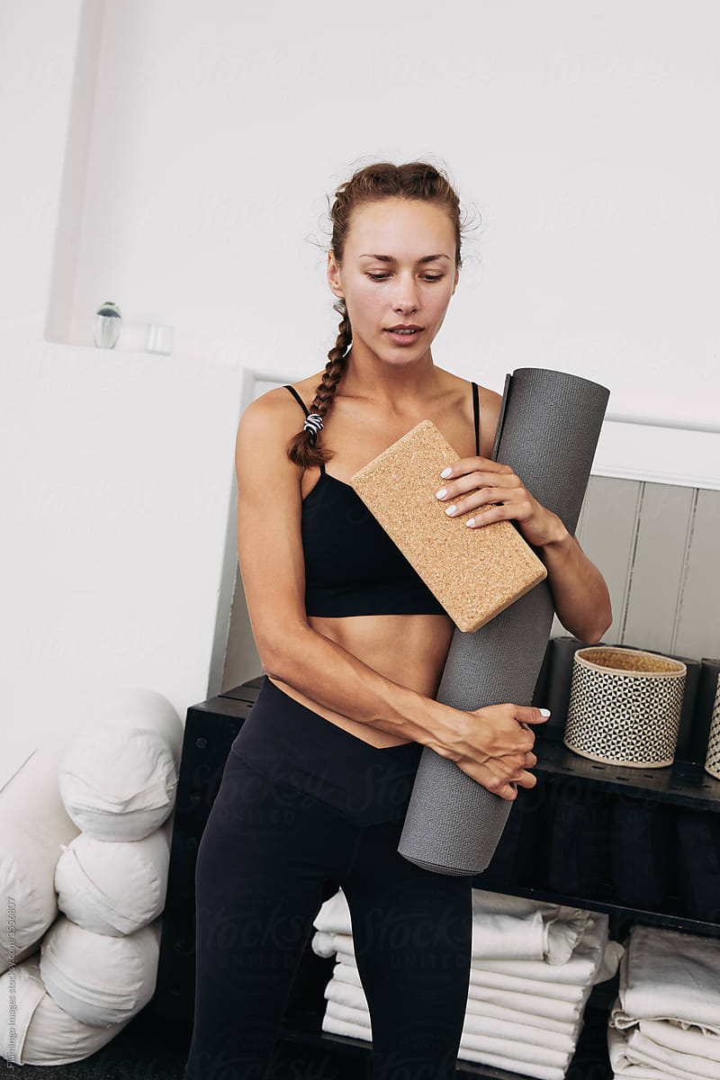 Fit woman holding a mat and yoga block