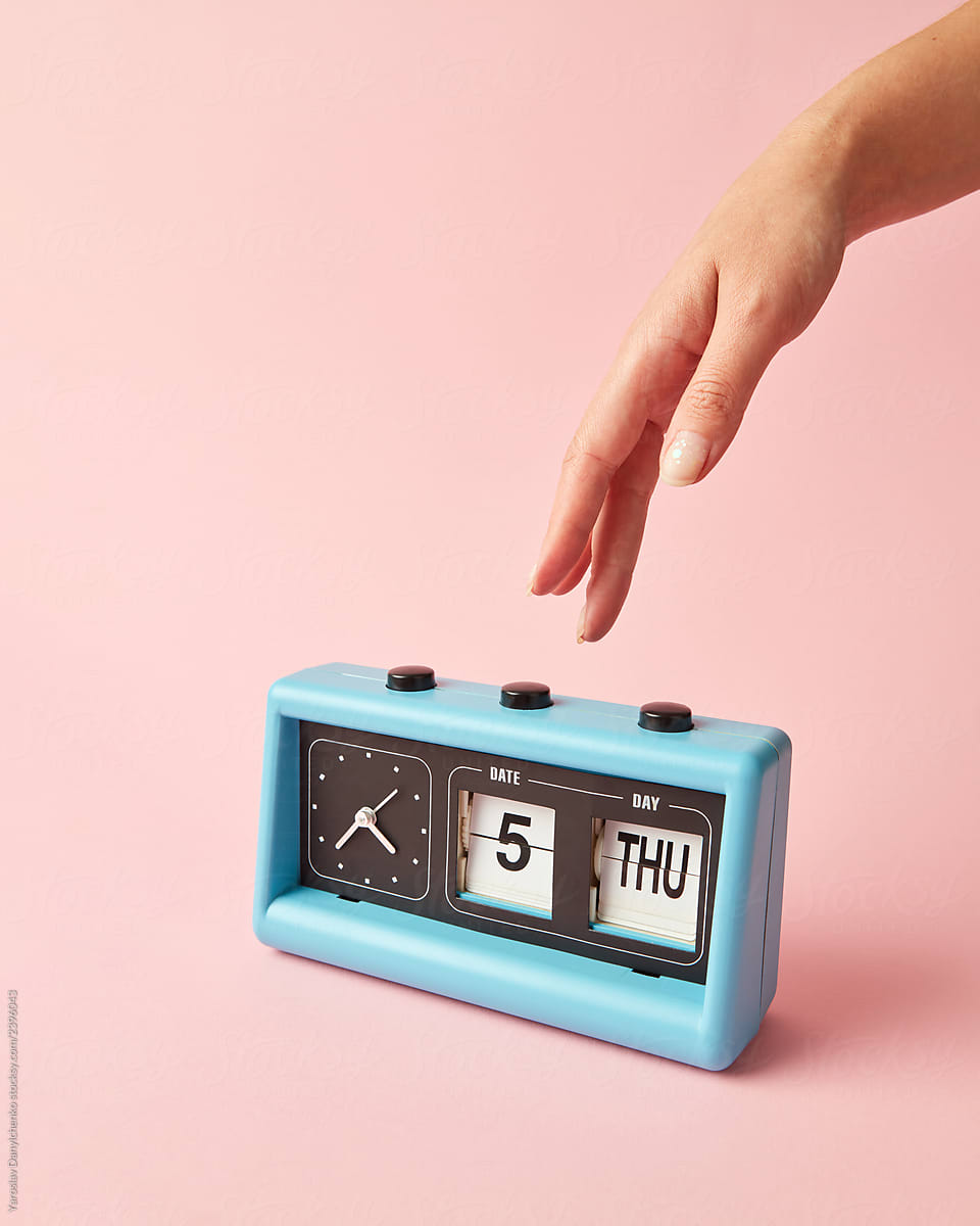 Woman\'s hand presses on the button on retro clock