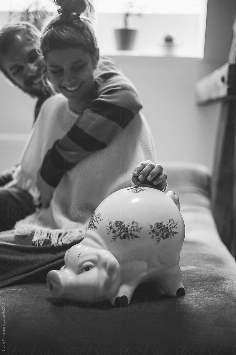Couple putting money in the piggy bank