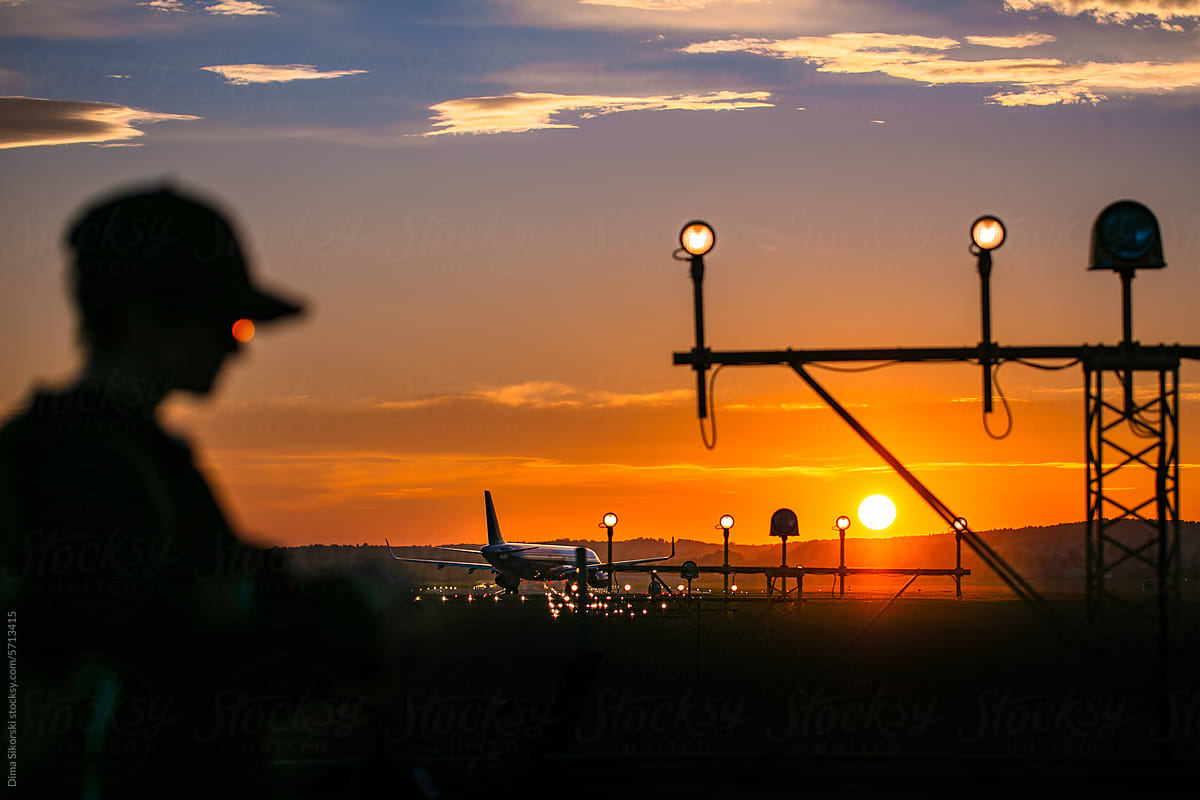 Silhouette of a man in a sunset airport with a plane on the runway