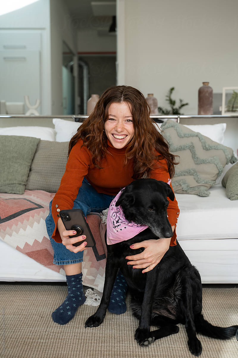 Woman taking selfie with dog at home