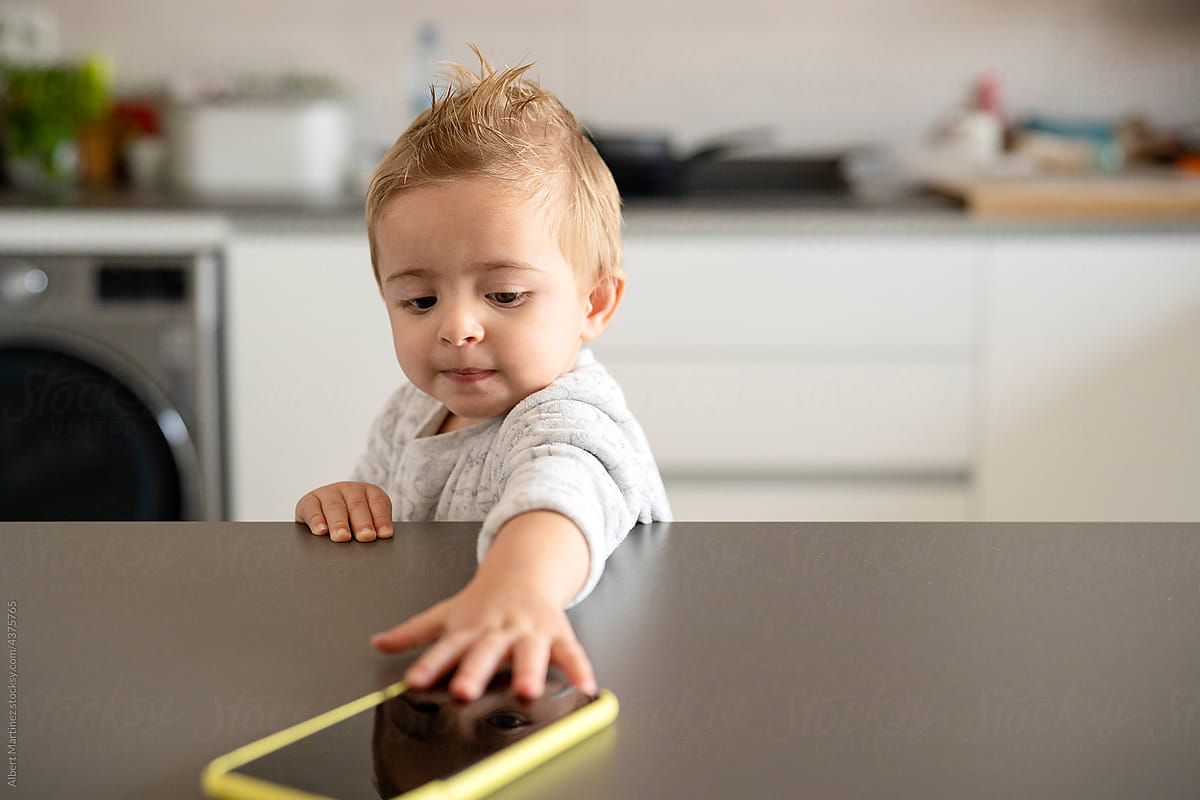 Toddler taking smartphone from table