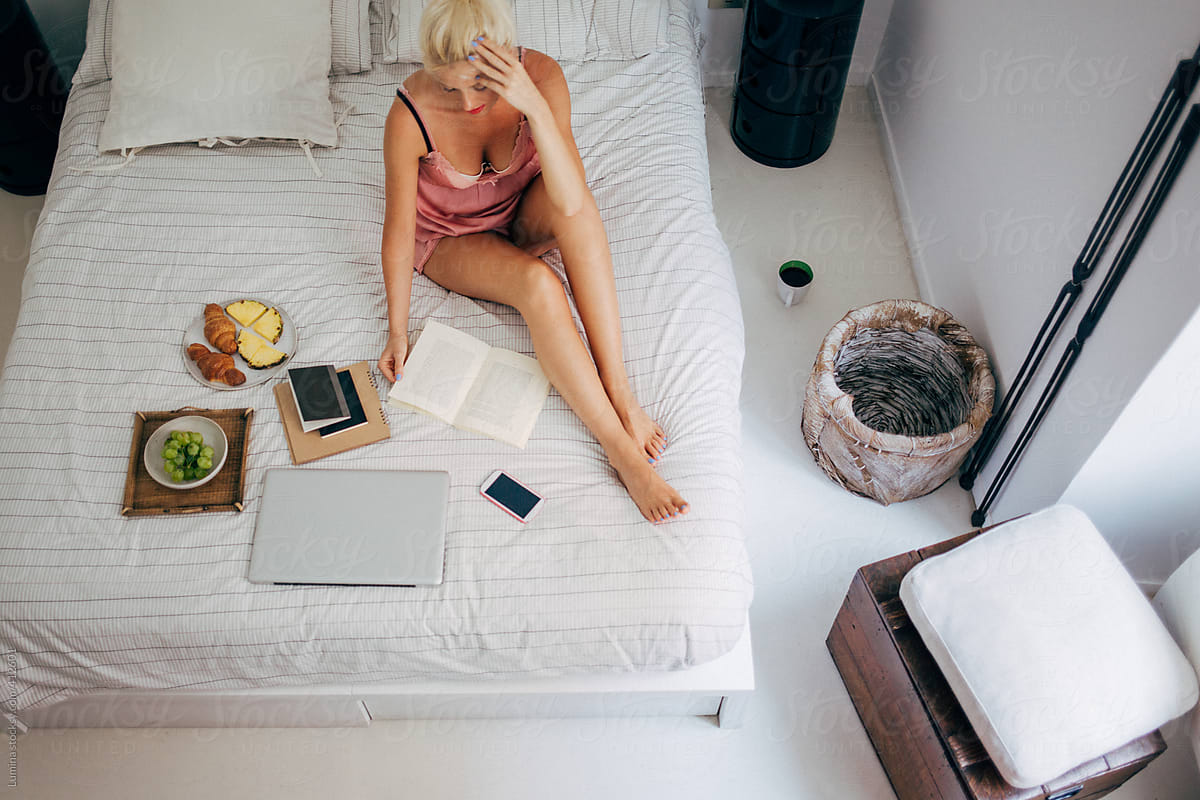 Woman Reading a Book and Having Breakfast in Bed