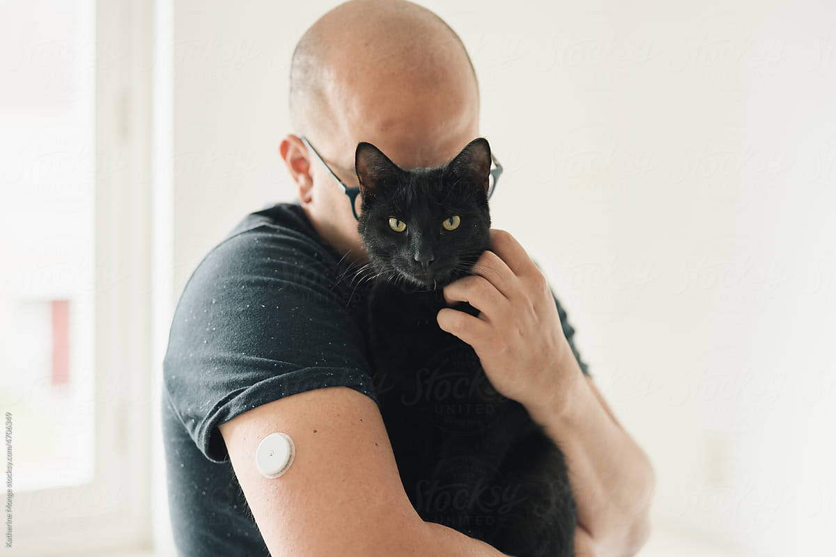 Man with glucose Monitor Sensor holding his cat
