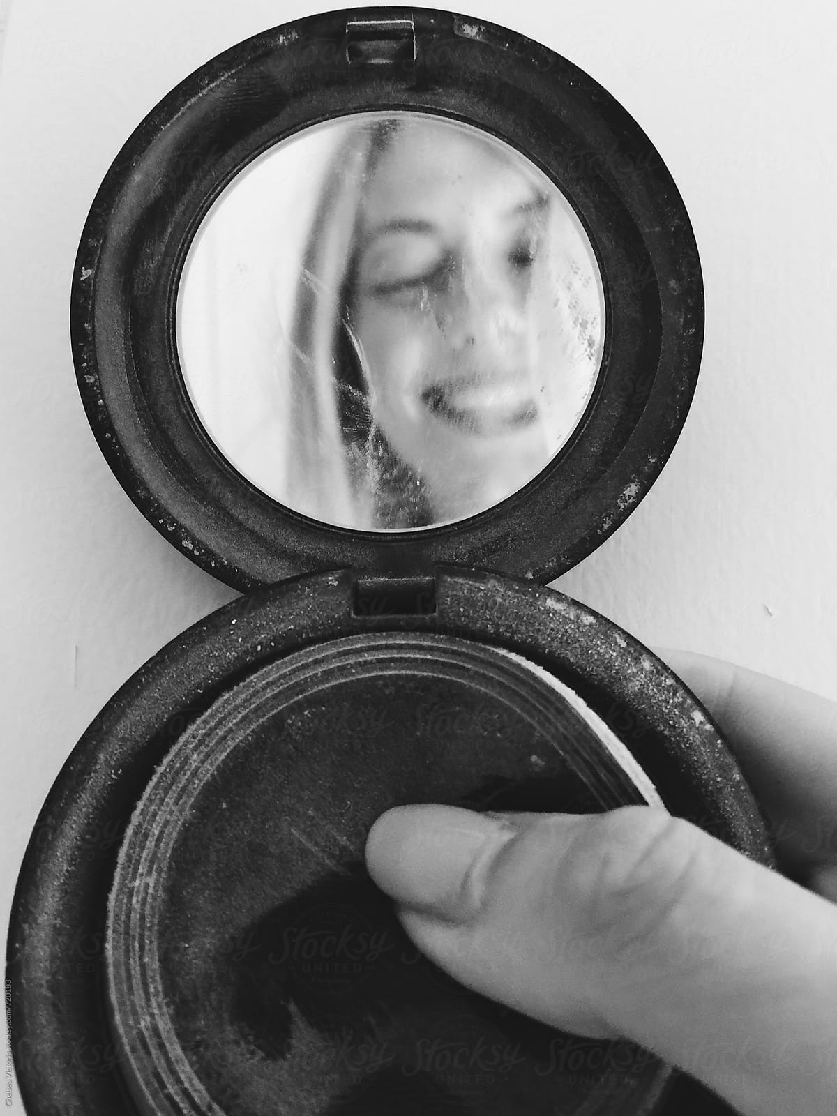 Series of self portraits of a woman making faces in a compact mirror.