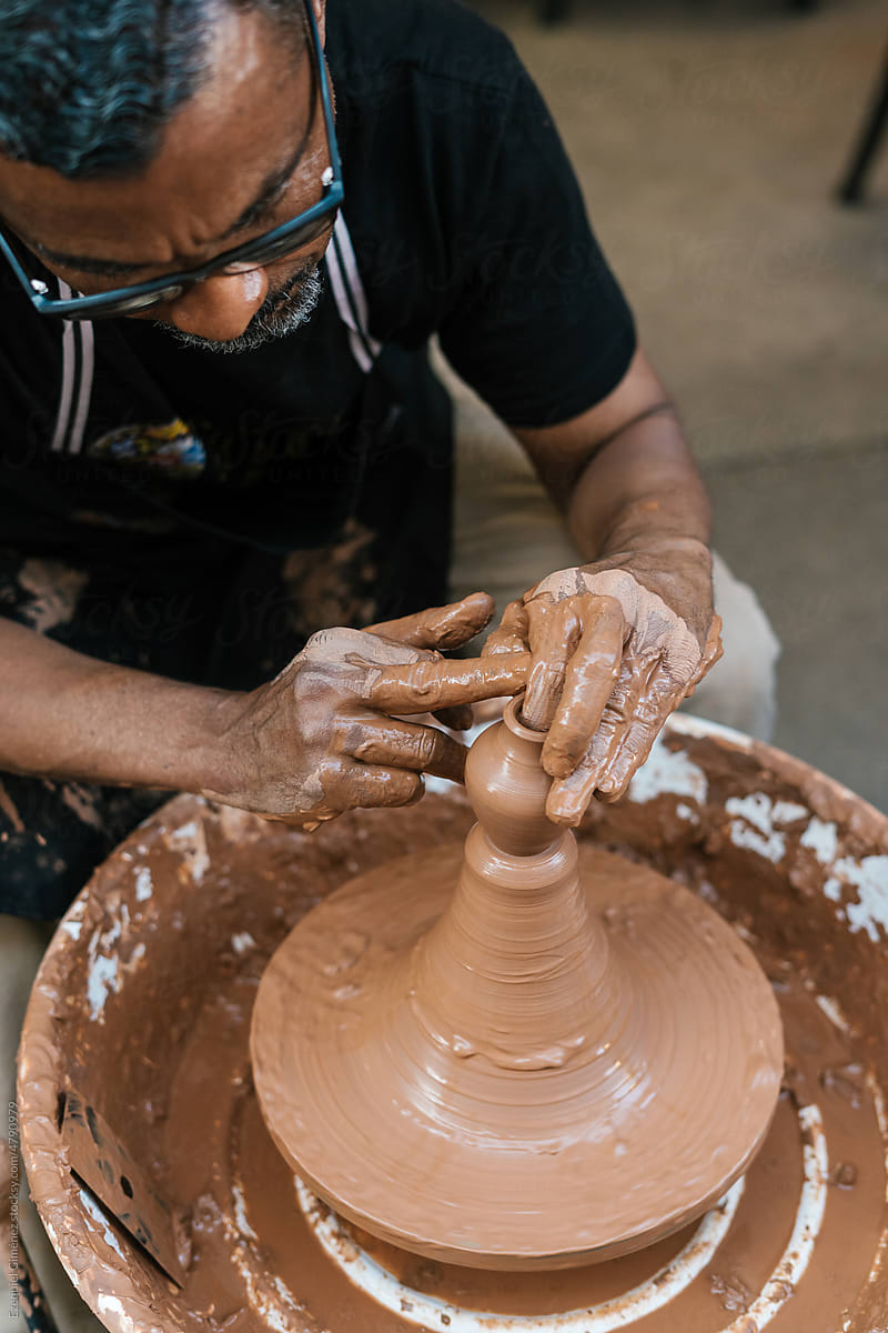 Man creating clay vessel in workshop