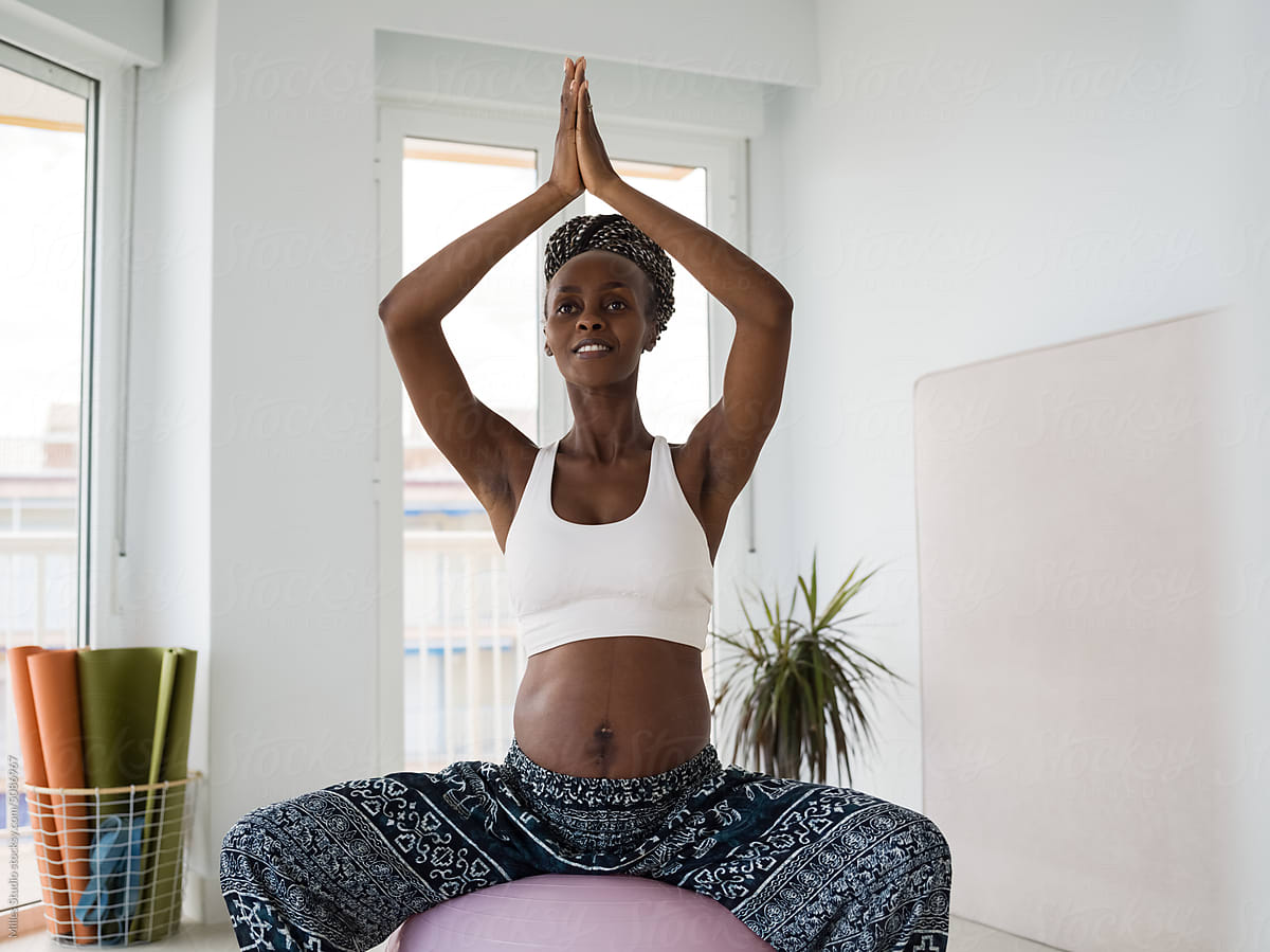 Smiling woman expecting baby meditating on yoga ball