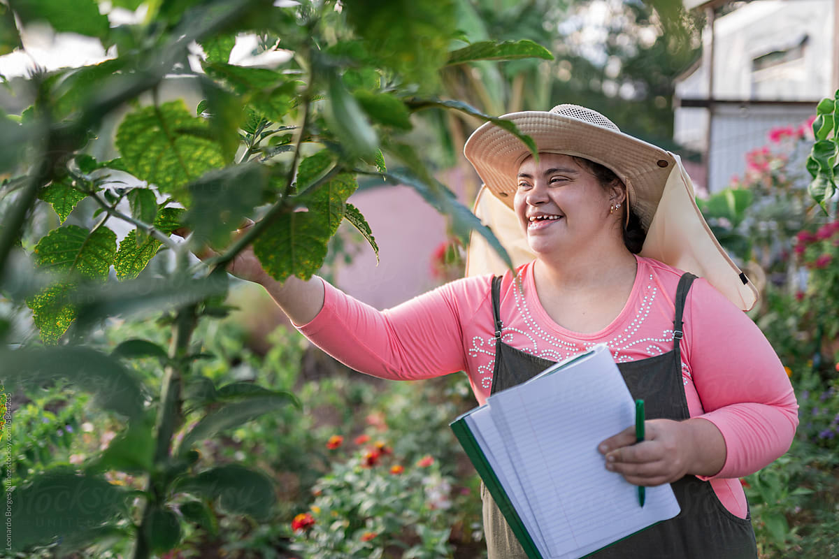 Woman with down syndrome smiles while touching plants