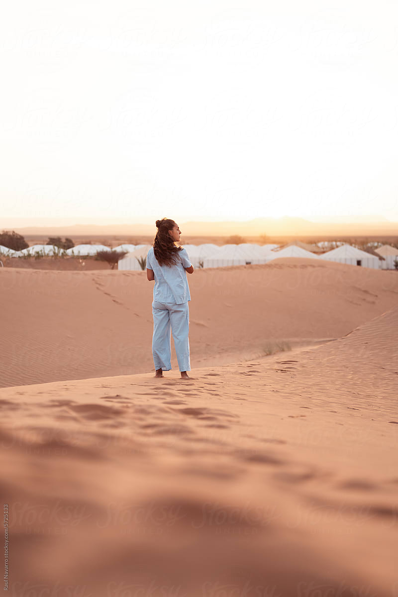 woman standing in the desert dunes admiring the sunrise.