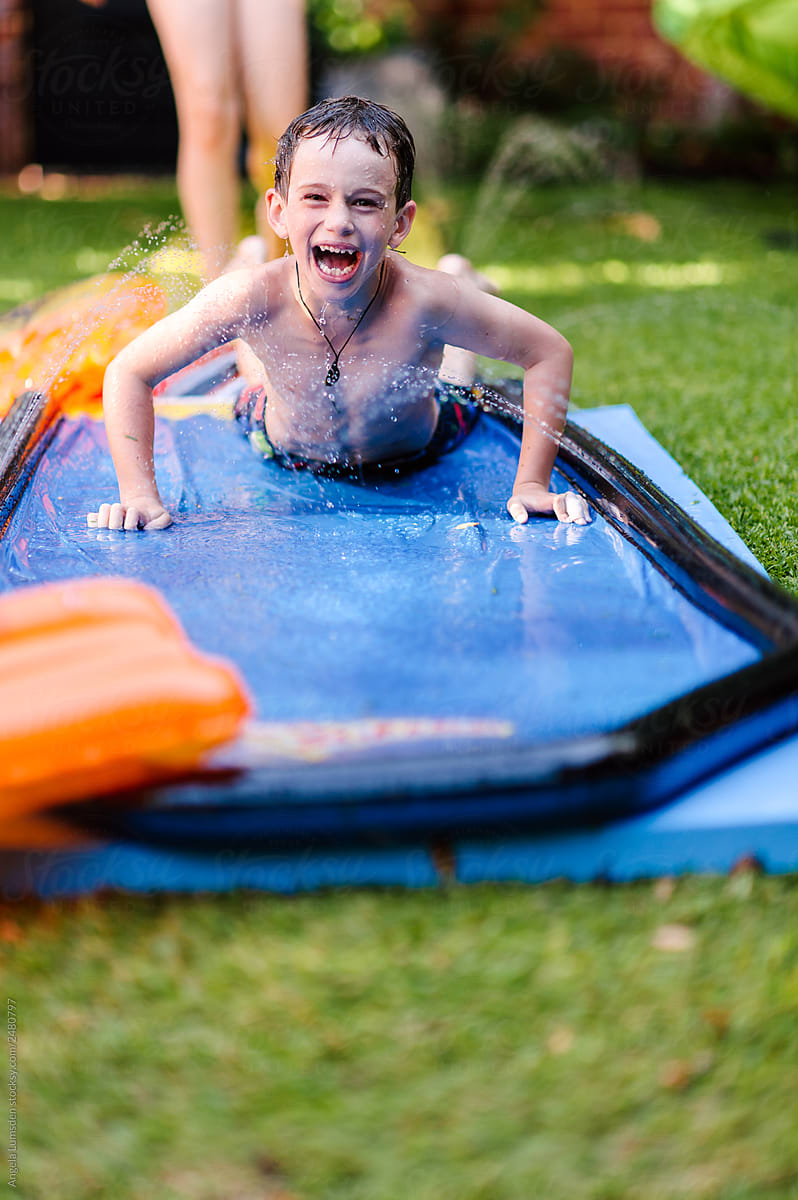 Children having fun on a slip and slide mat in summer