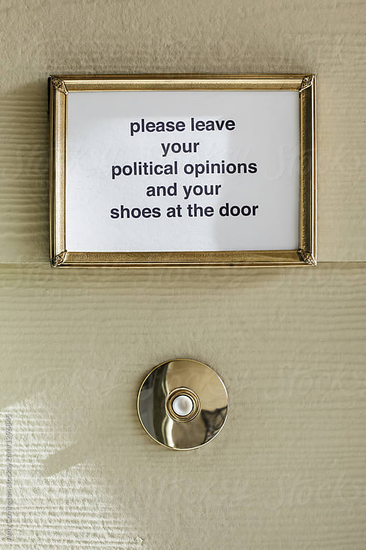 A sign above a door bell that reads - please leave your political opinions and shoes at the door