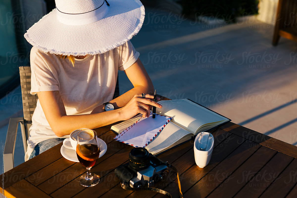 Woman behind a white hat in café at sunset