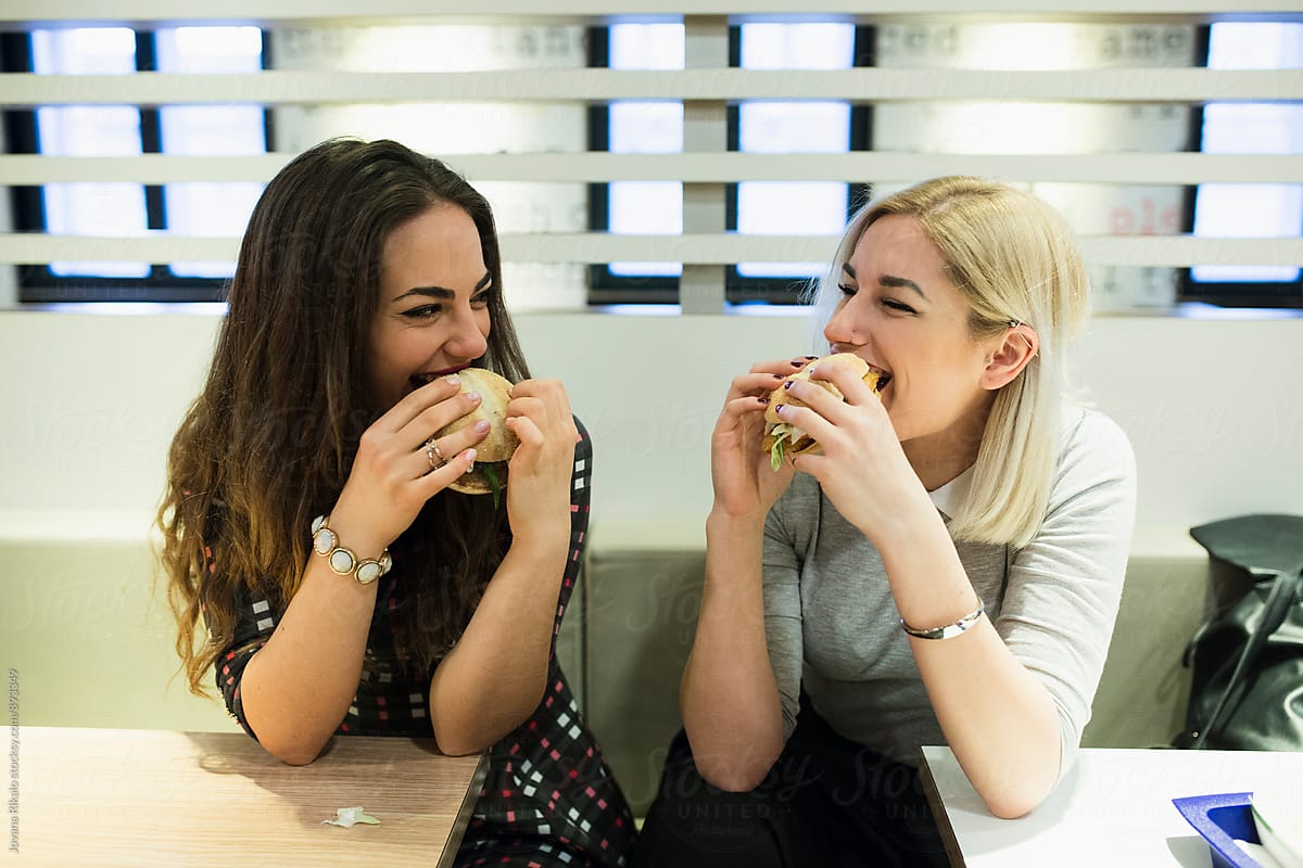 Two female friends eating burgers