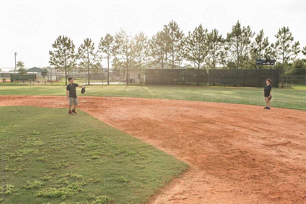 Two Boys Play Catch On A Baseball Diamond