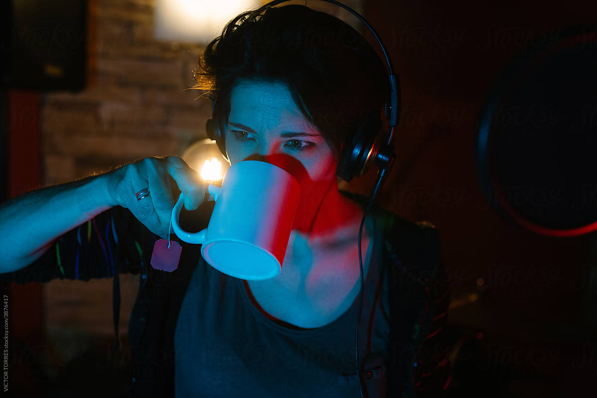 Singer in headset with hot drink in recording studio