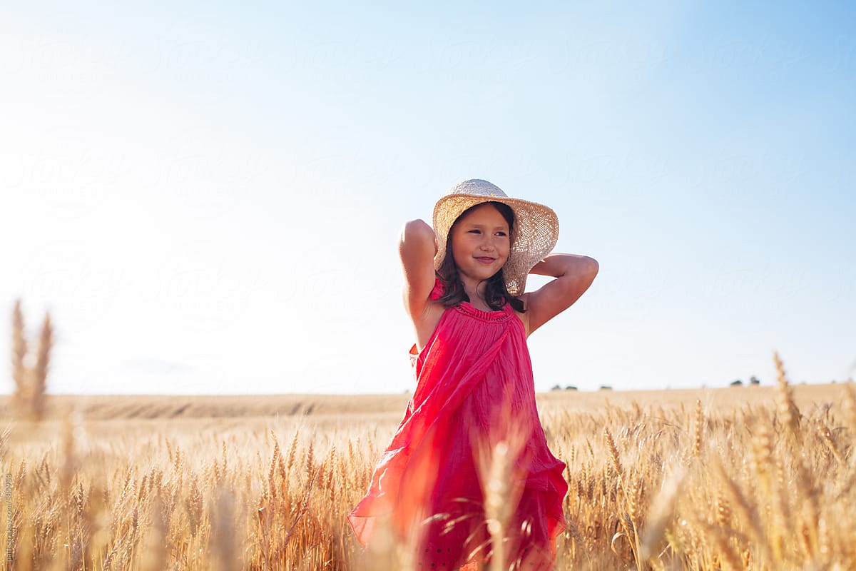 Portrait of a beautiful little girl in pink dress posing on a wheat field