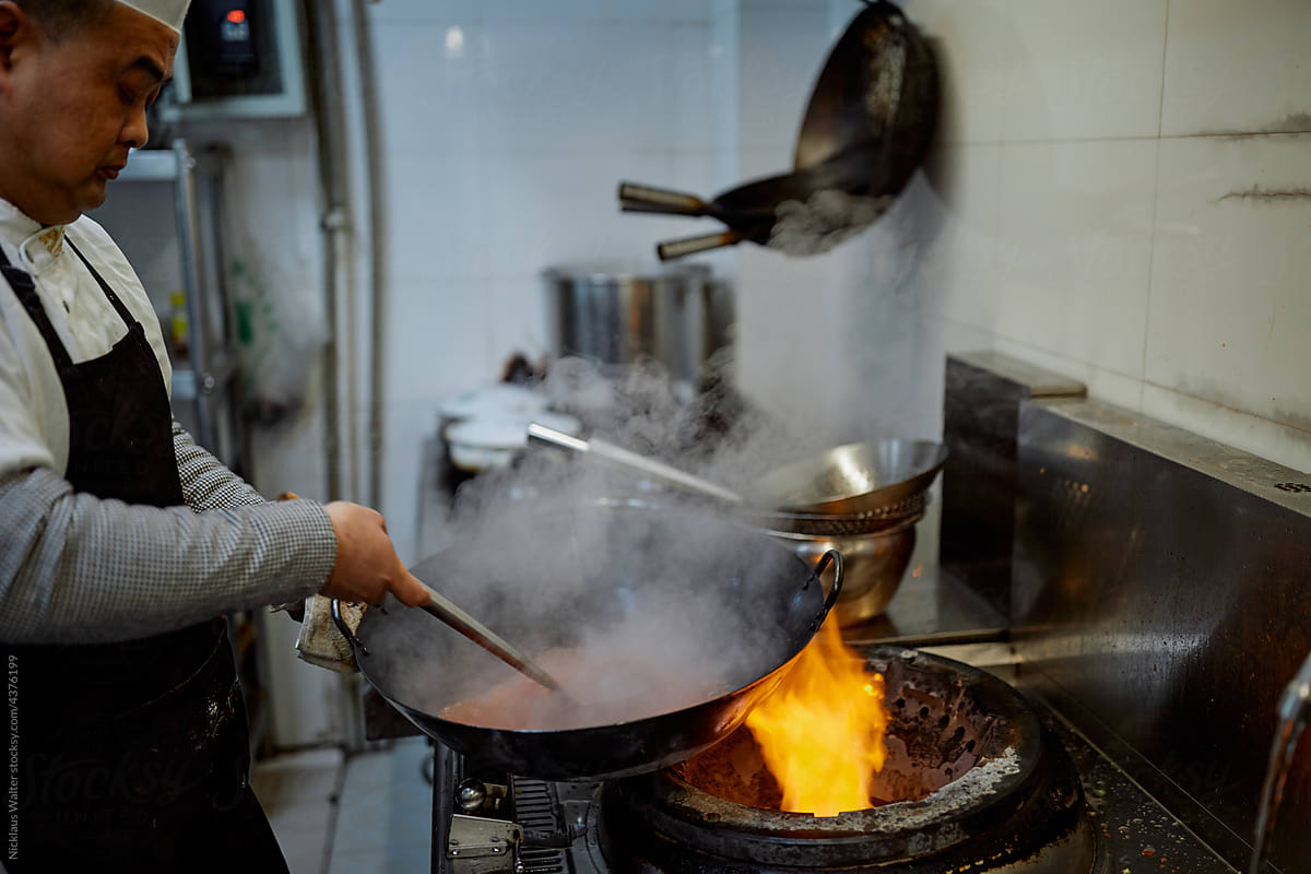 Chinese chef prepares sauce in a restaurant kitchen