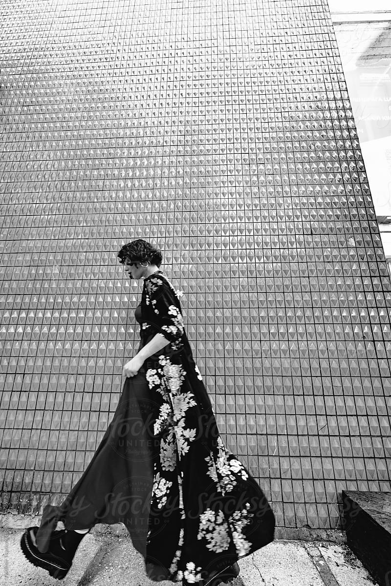 fashionable woman walking in long dress along the wall in the city