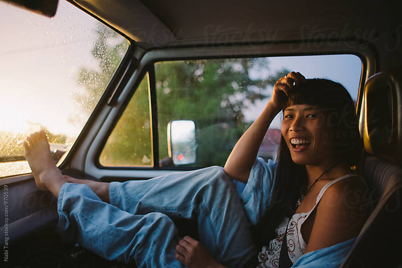 Asian young woman enjoying sunset in the front seat of the camper van
