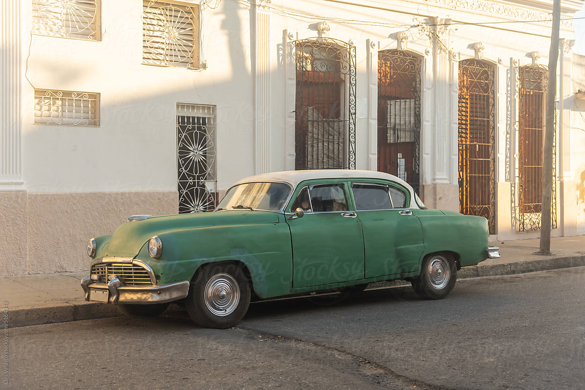 Green Vintage Car Parked Near Antique Building In Cuba.