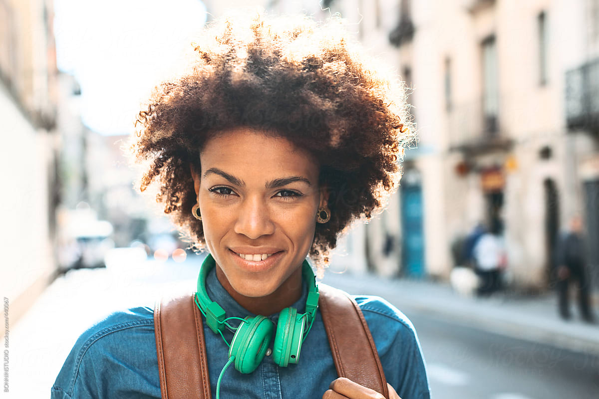 Afro American Woman With Leather Backpack And Green Headphones Smiling
