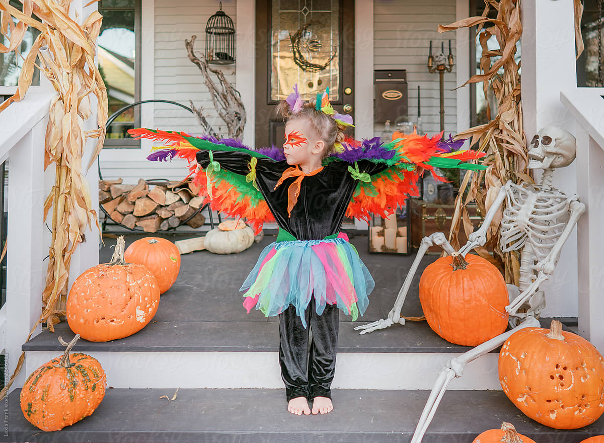 little girl in homemade bird costume on halloween posing on her front porch