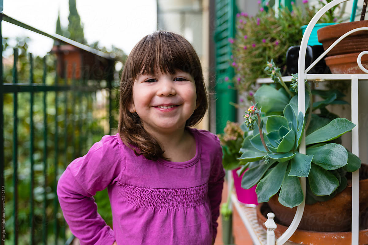 Cheerful toddler standing near plants on balcony