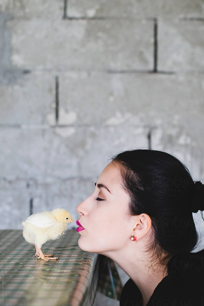 Young woman kissing baby chick