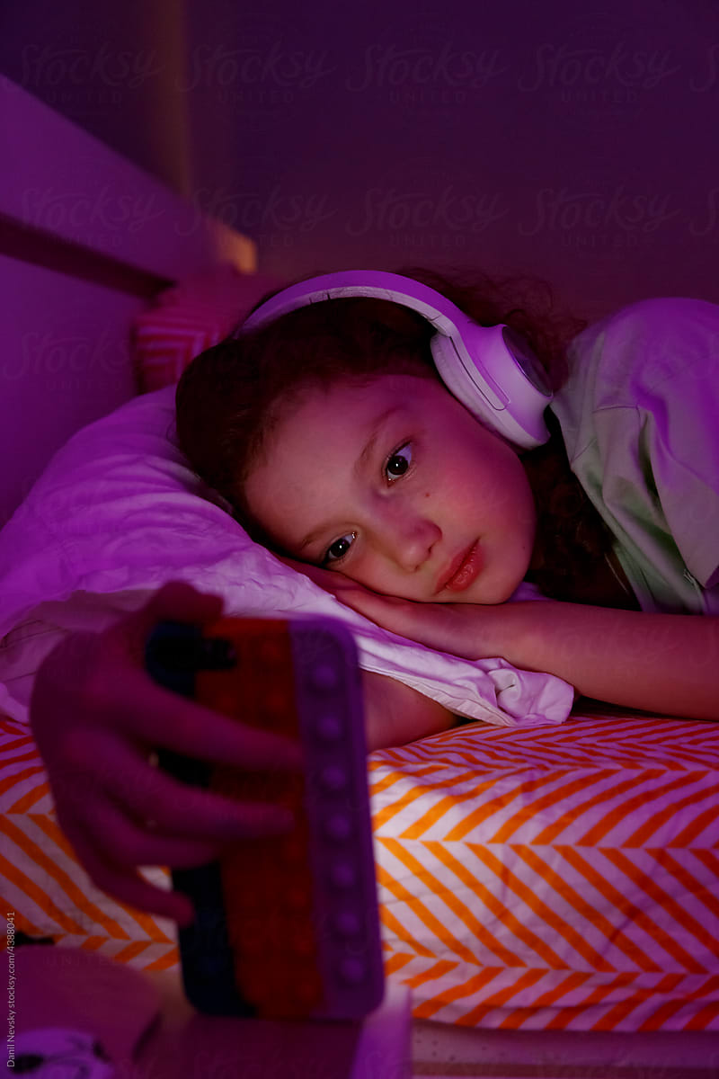 Sleepy girl watching video on smartphone on bed