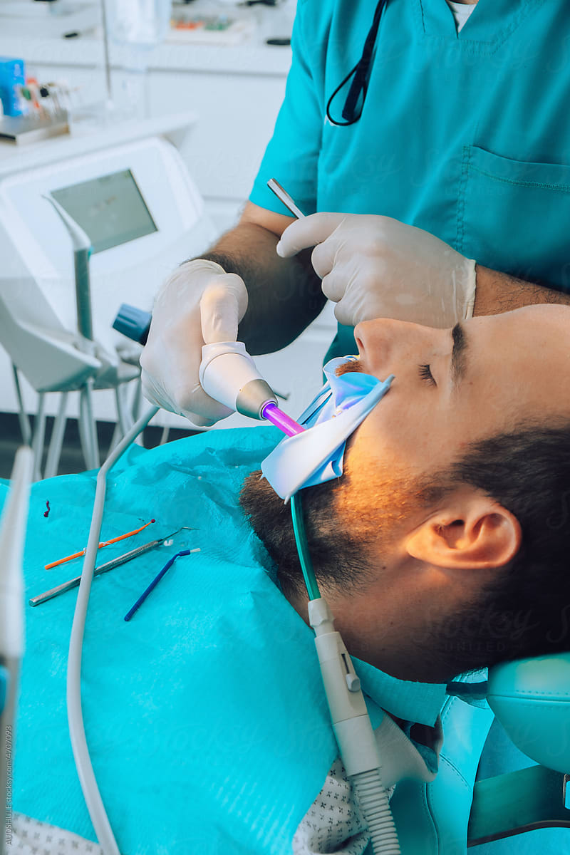 Dental Surgeon Making New Tooth filling with UV light