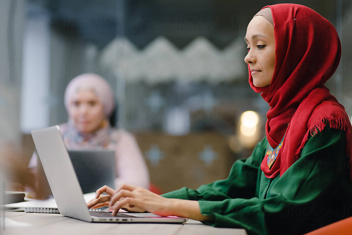 Focused Muslim businesswoman using laptop in modern workplace