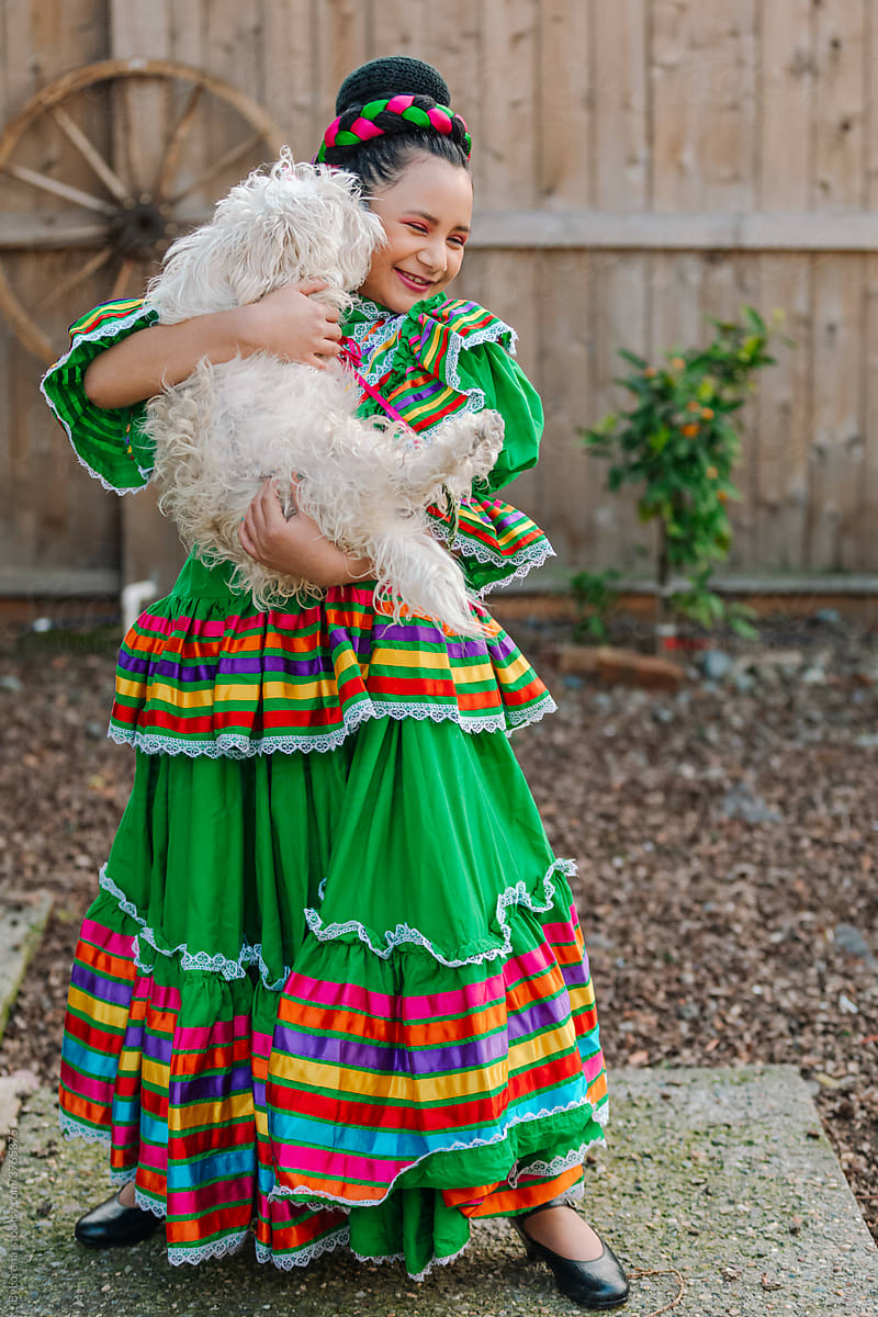 Happy girl on traditional dress playing with dog
