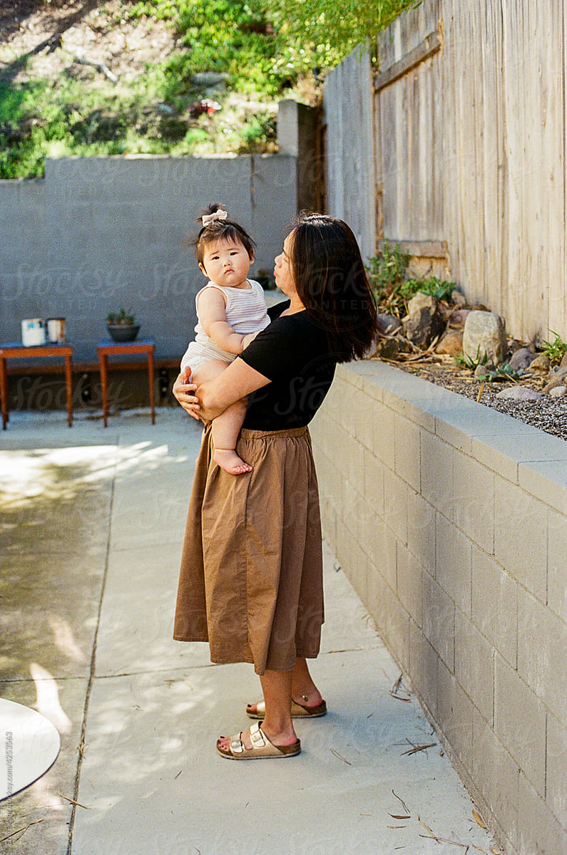 Asian mom holding young daughter outside