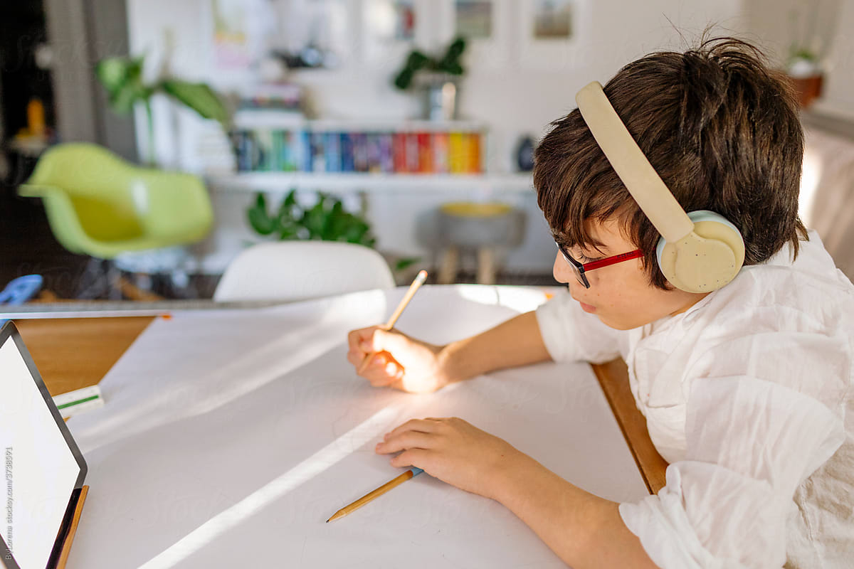 Side view Boy wearing white shirt and headphone drawing over roll paper