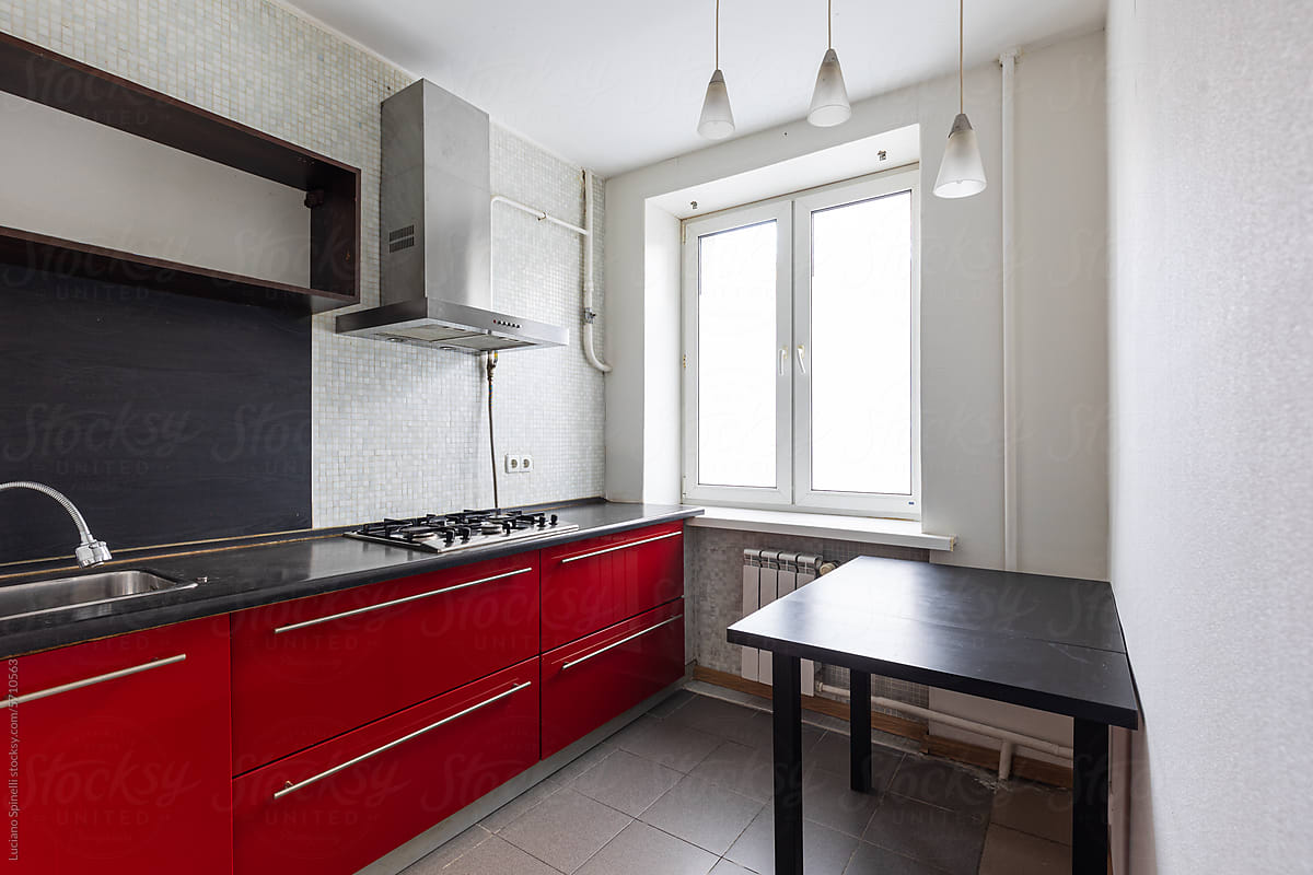 Small minimal empty red kitchen with a black table and a kitchen hood