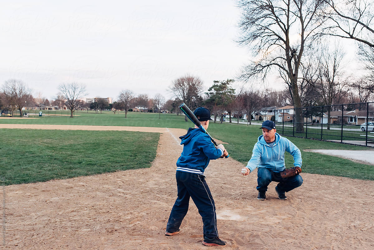 Dad and son practicing hitting a ball with a baseball bat