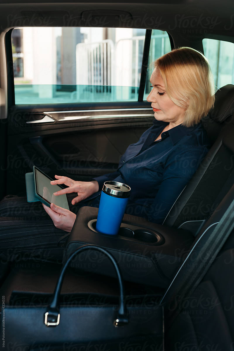 Middle-aged woman in car with tablet.