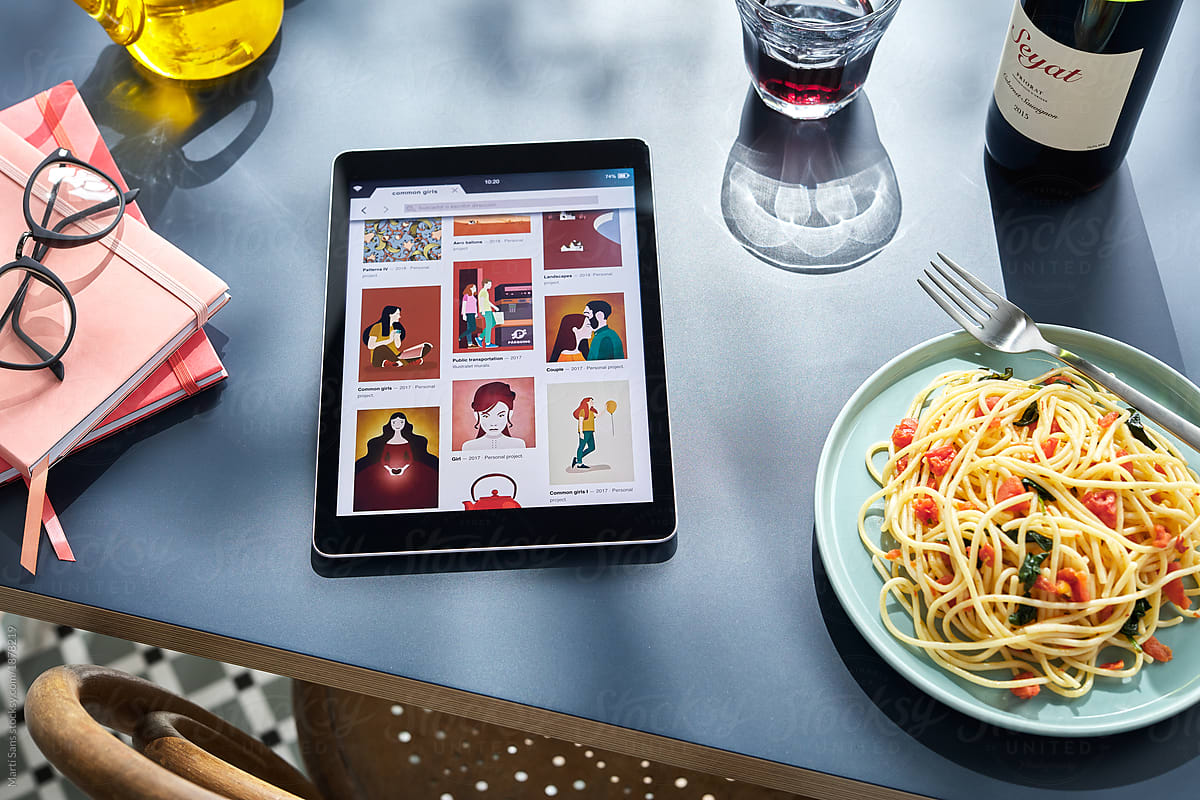 Tablet with pics, spaghetti and notebooks with wine.
