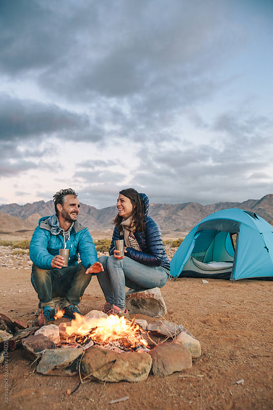 Hiker couple sitting at a camp fire amongst rugged desert mountains