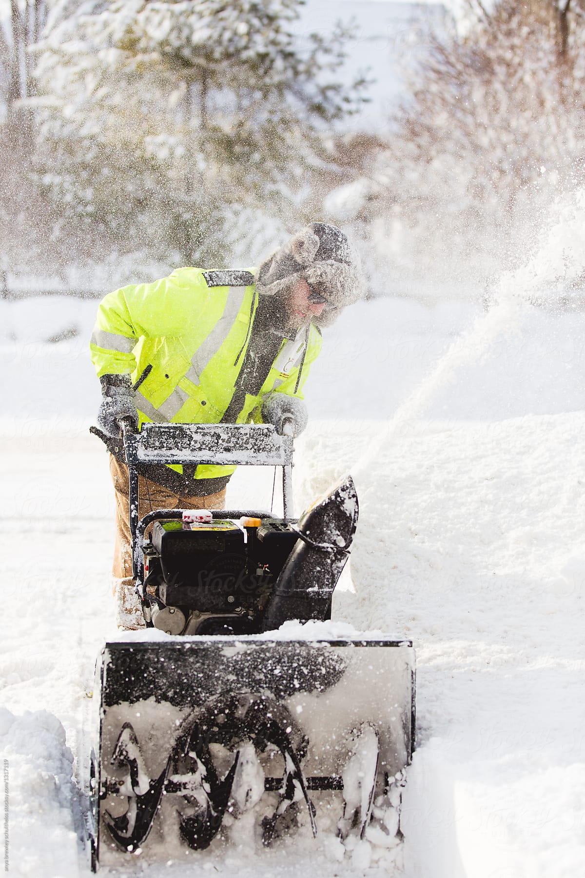 Man using a snow blower to clean his walkway.