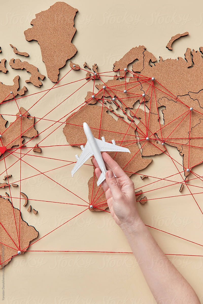 Woman holding plane model near map with red connections