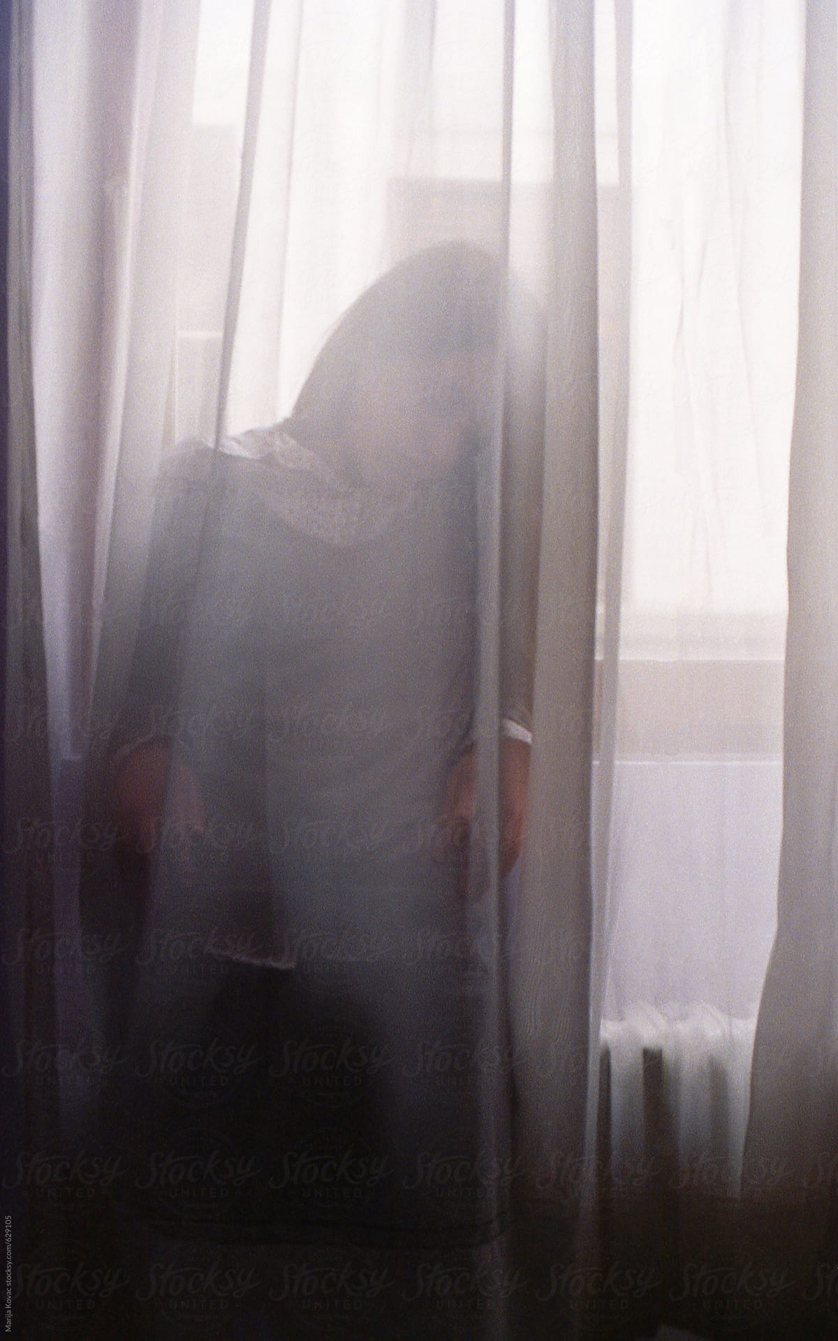 Young woman standing behind the curtain